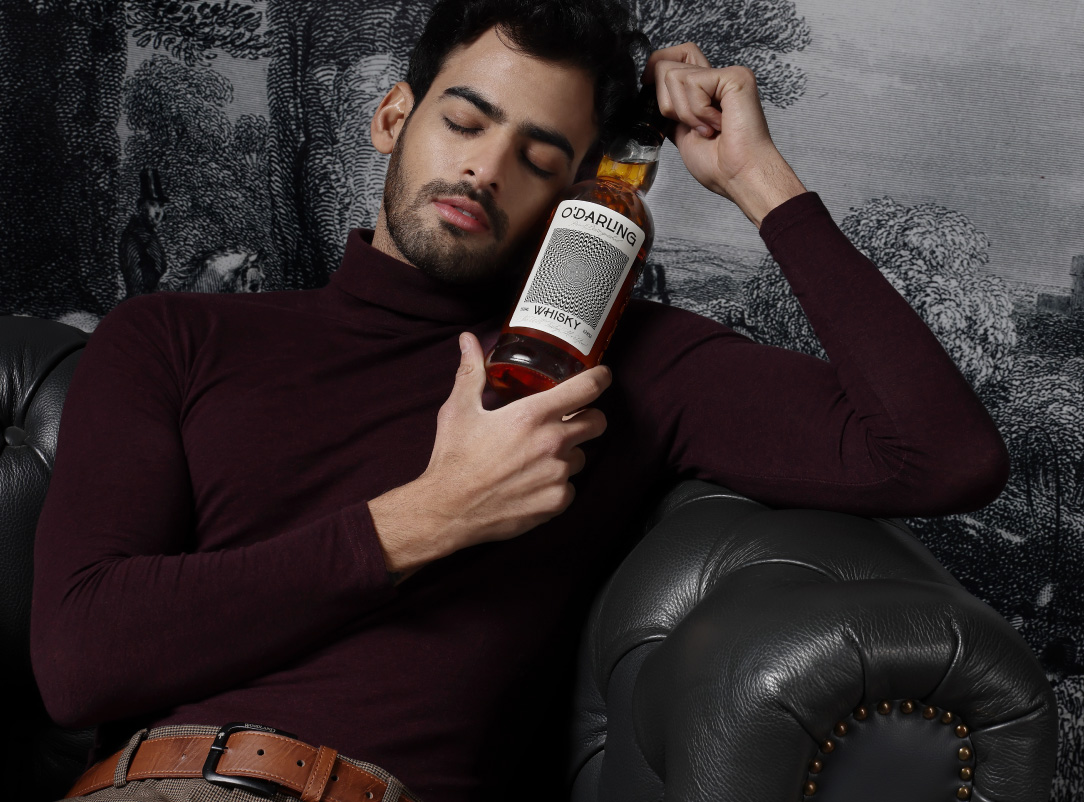 Image of a man sitting on the couch with a bottle of O'Darling Whisky