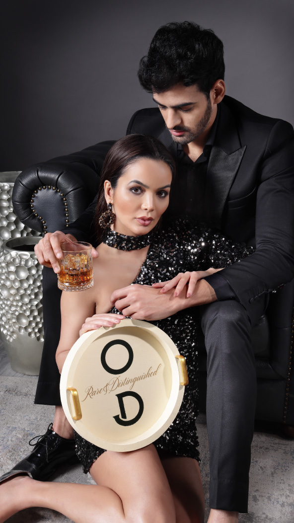  A man and woman celebrating with O'Darling Whisky. The woman is holding a tray while the man holding a glass filled with O'Darling Whisky